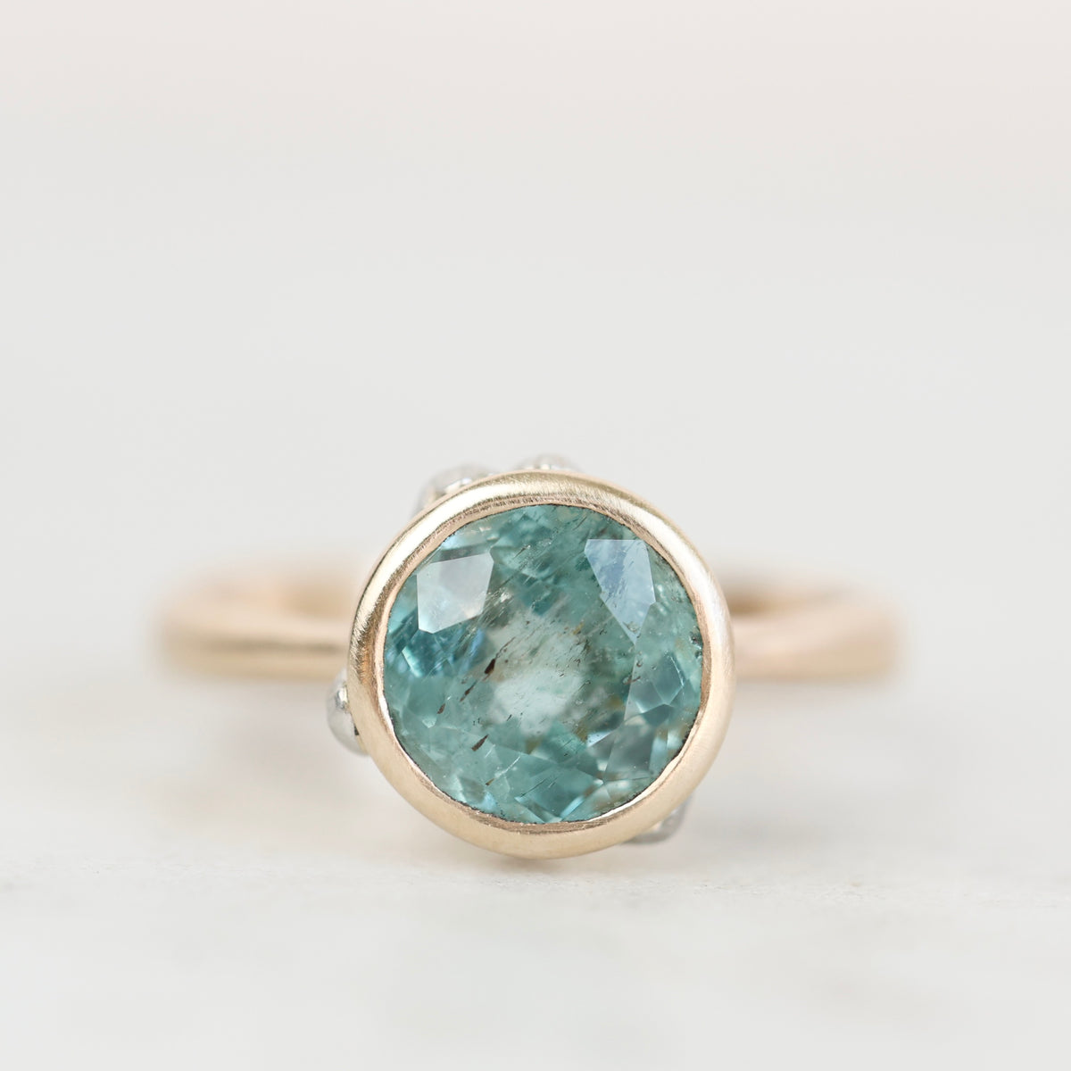 Bezel set ring with blue green stone with inclusions. 
