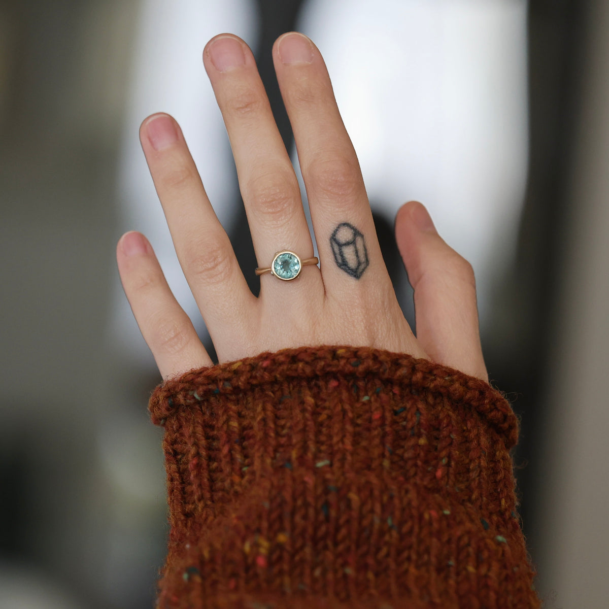 Hand wearing blue gemstone ring. 
