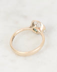 Ring facing away gold with bezel setting and platinum barnacle details against a plain background. 