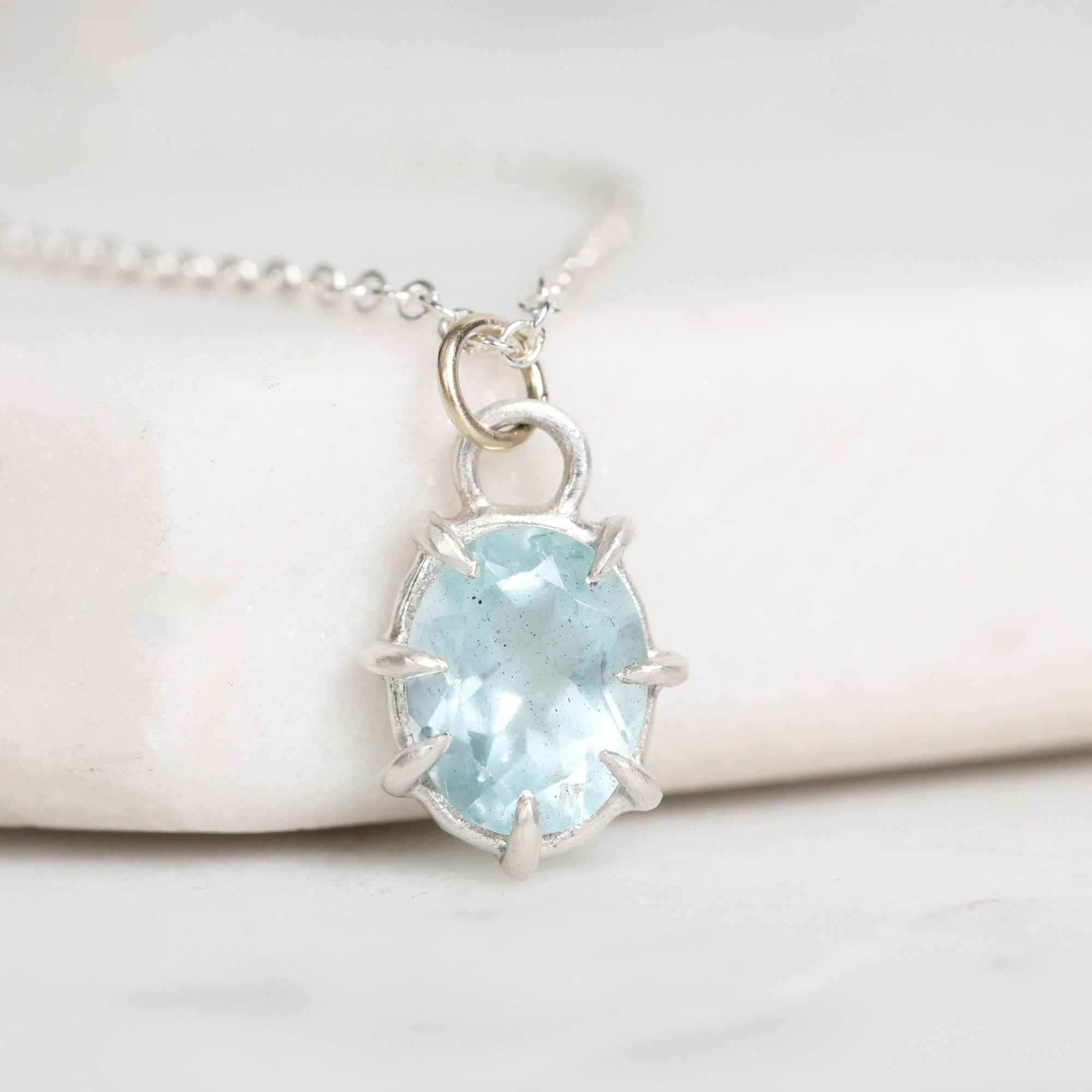 Necklace with a light blue gemstone pendant on a white background