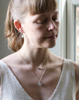 Woman wearing a necklace with a pendant in a softly lit room.