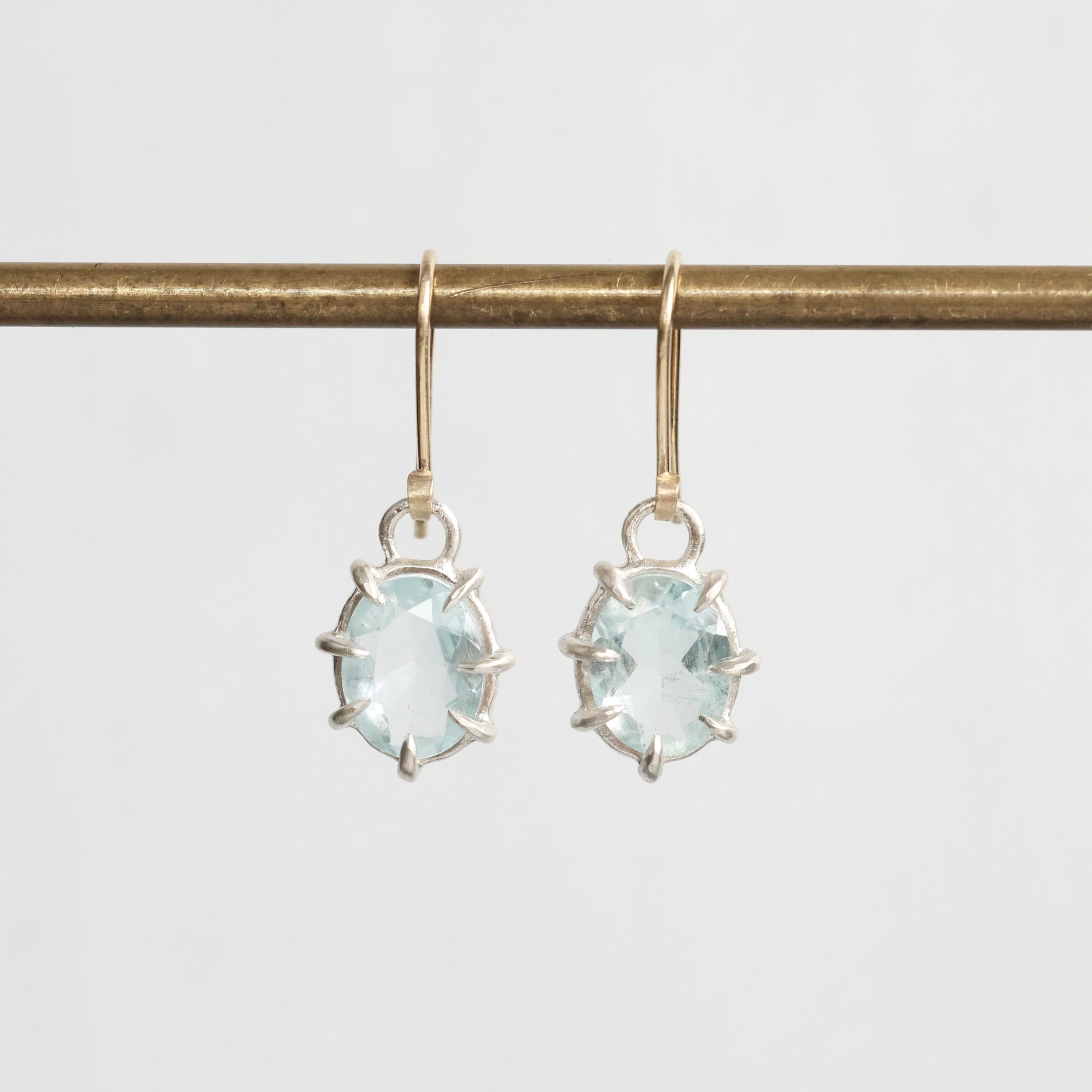 Gold earrings with light blue gemstones on a white background