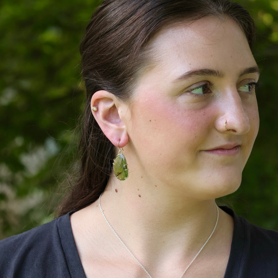 Green drop earrings on woman with brown hair. 