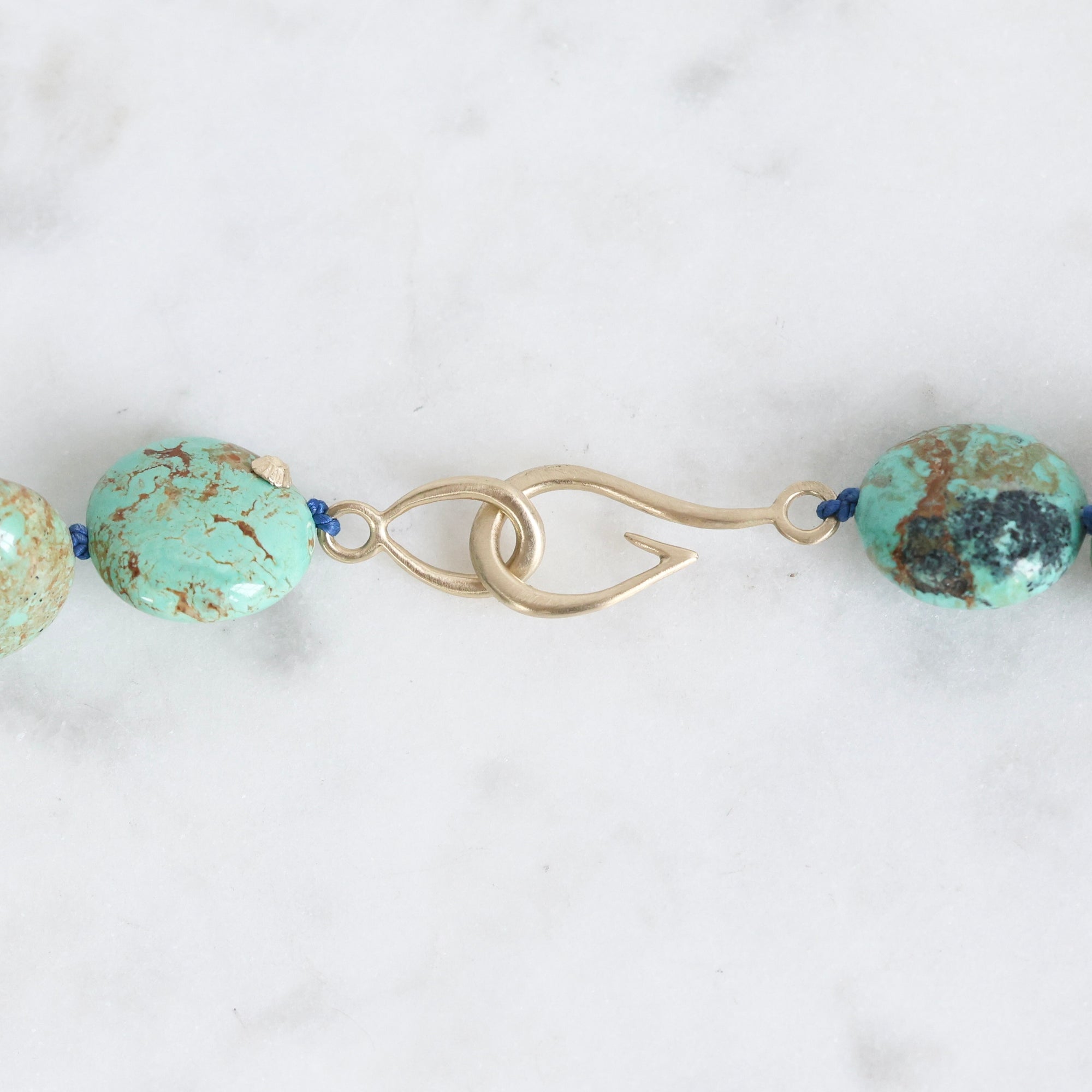 Turquoise beaded necklace with gold clasp on a white background