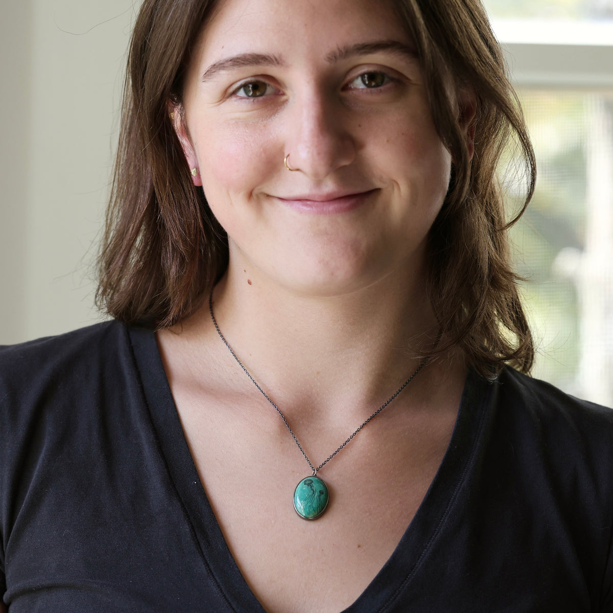 Woman wearing turquoise necklace against a blurred indoor background
