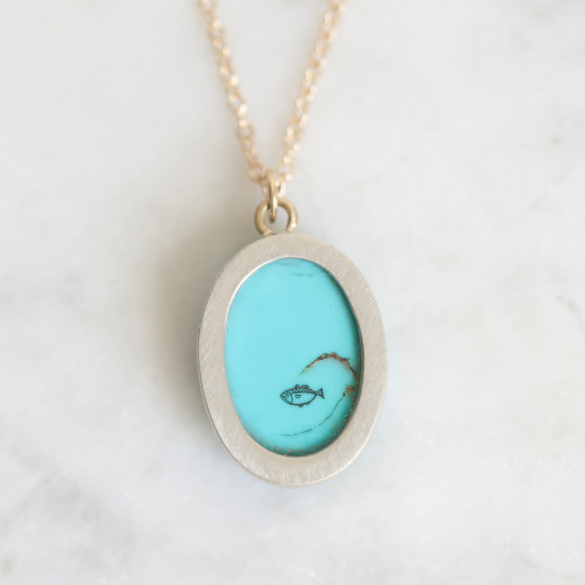 Back of necklace with a small scrimshaw fish. 