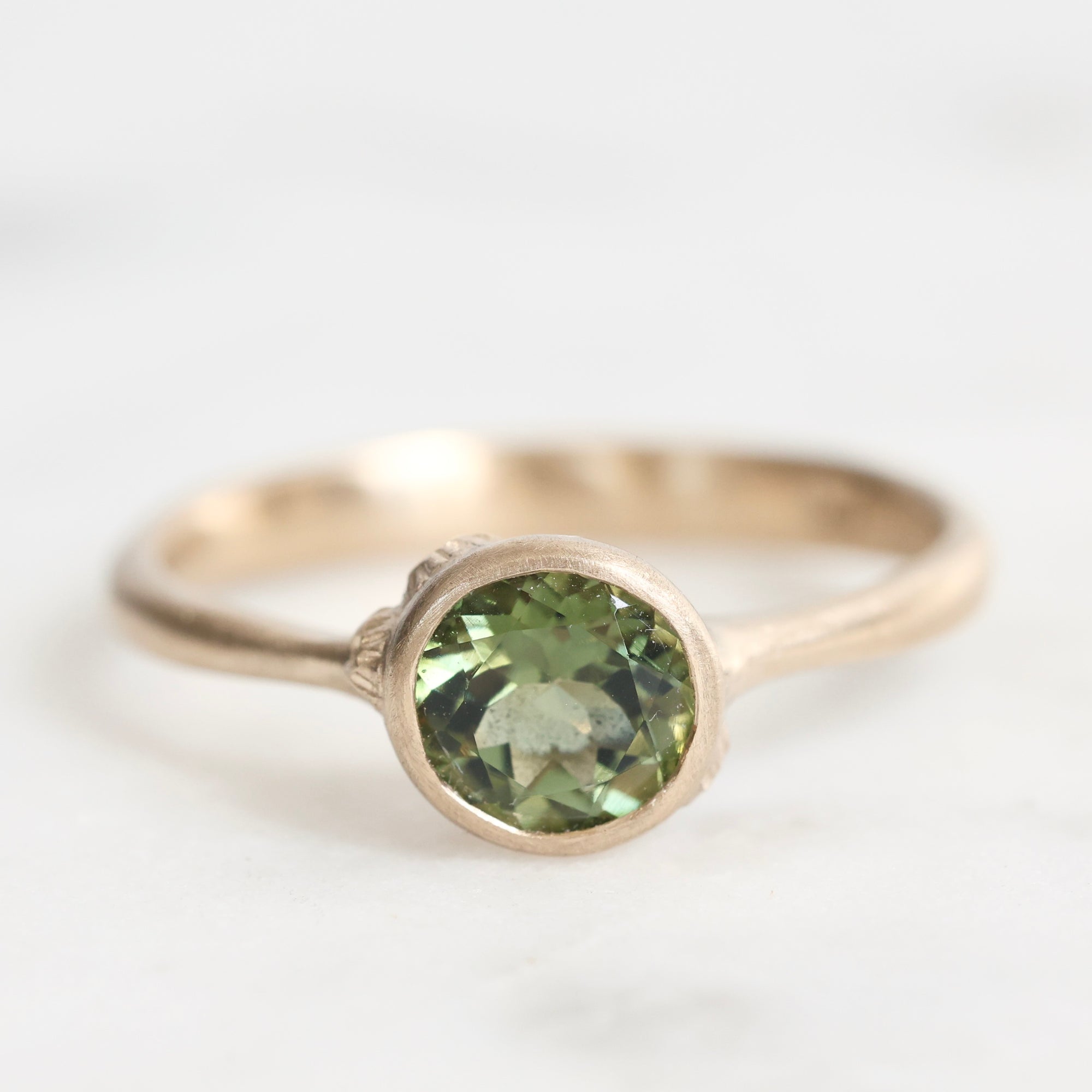Gold ring with a green gemstone on a white background