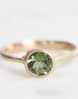 Gold ring with a green gemstone on a white background