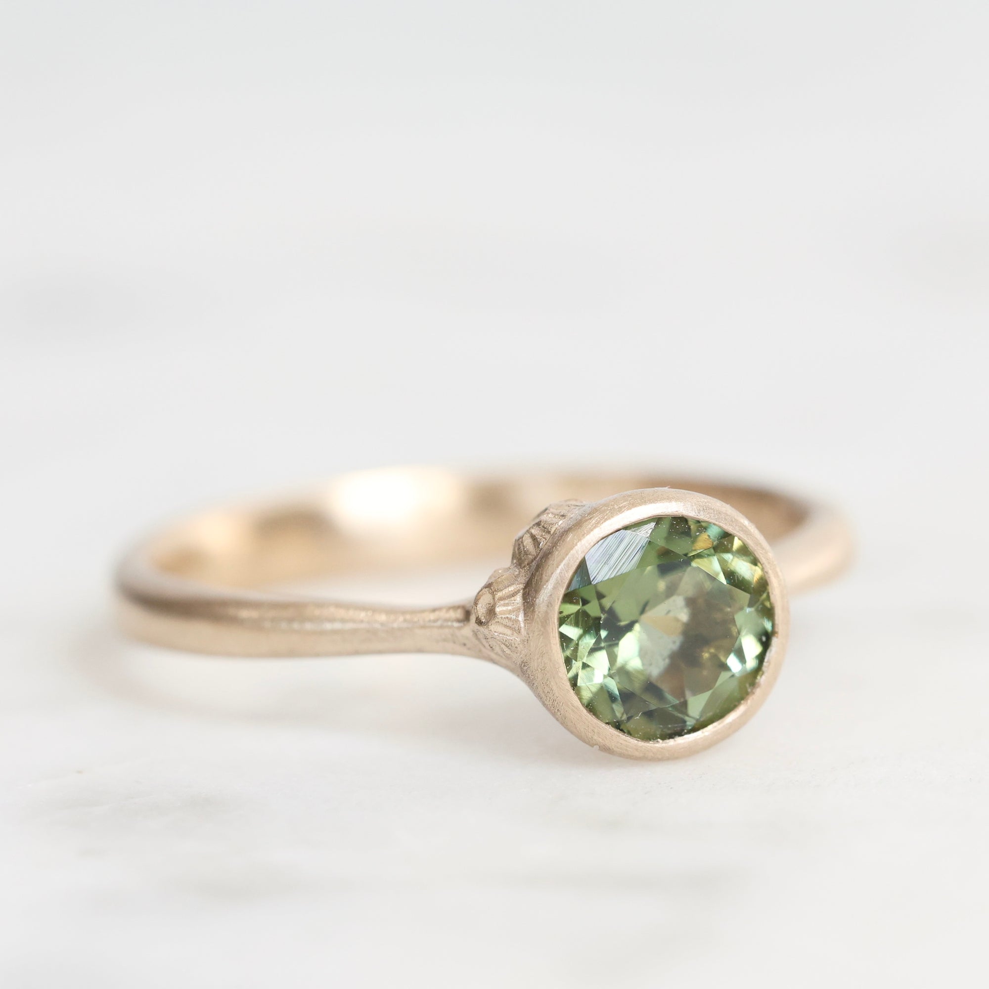 Gold ring with a green gemstone on a white background