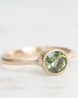 Gold ring with a green gemstone on a white background