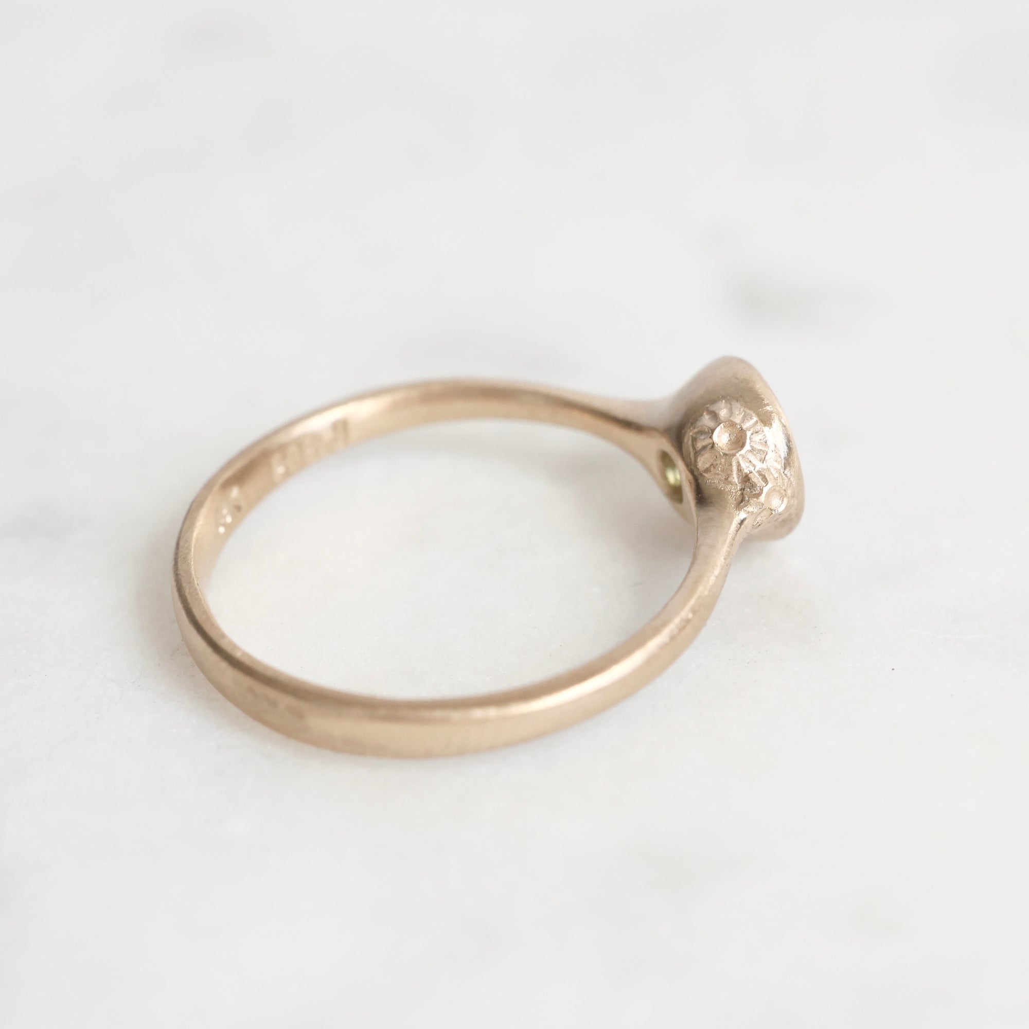 Gold ring with a small decorative element on a white background