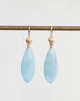 Pair of light blue teardrop earrings with gold hooks on a white background