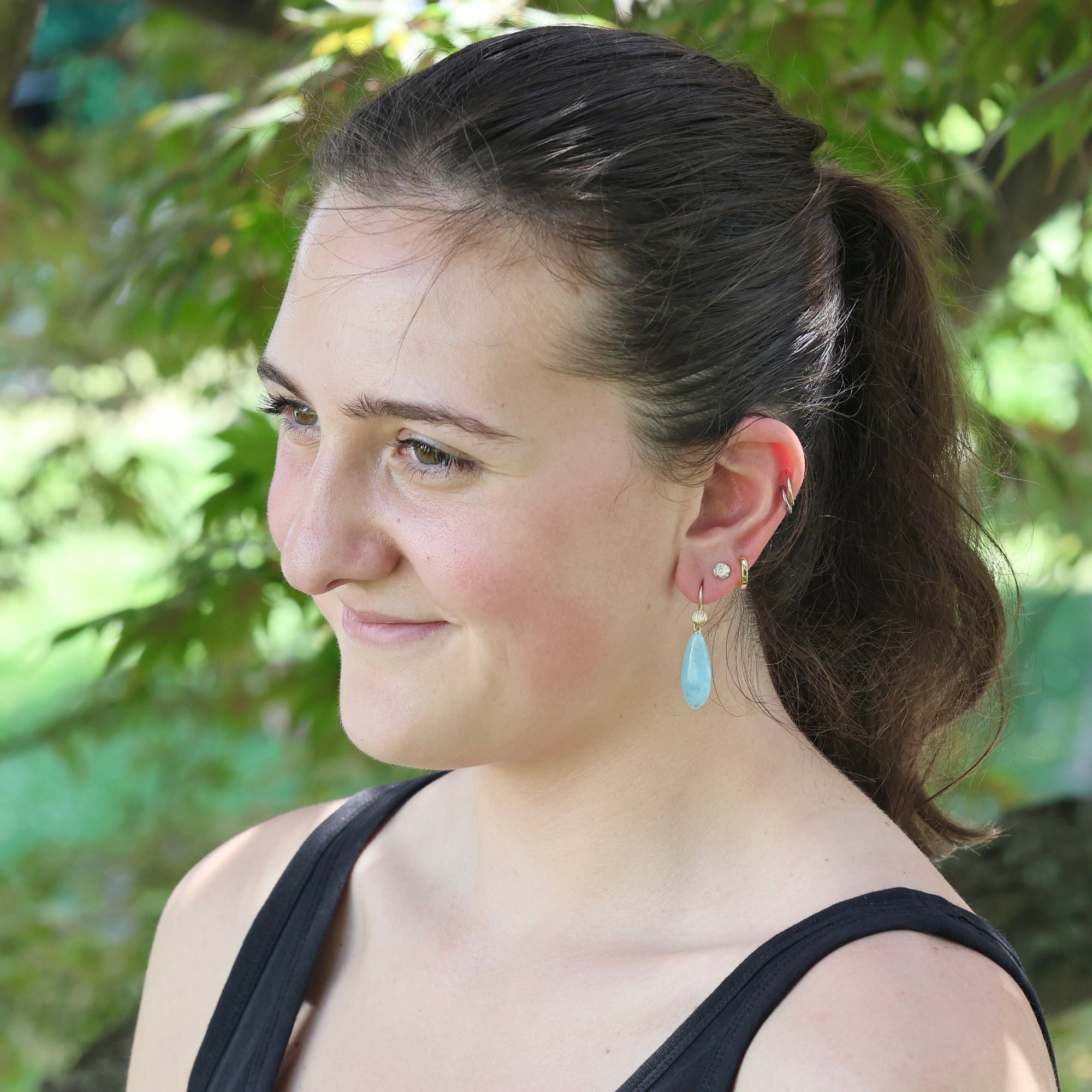 Woman with a ponytail wearing earrings outdoors