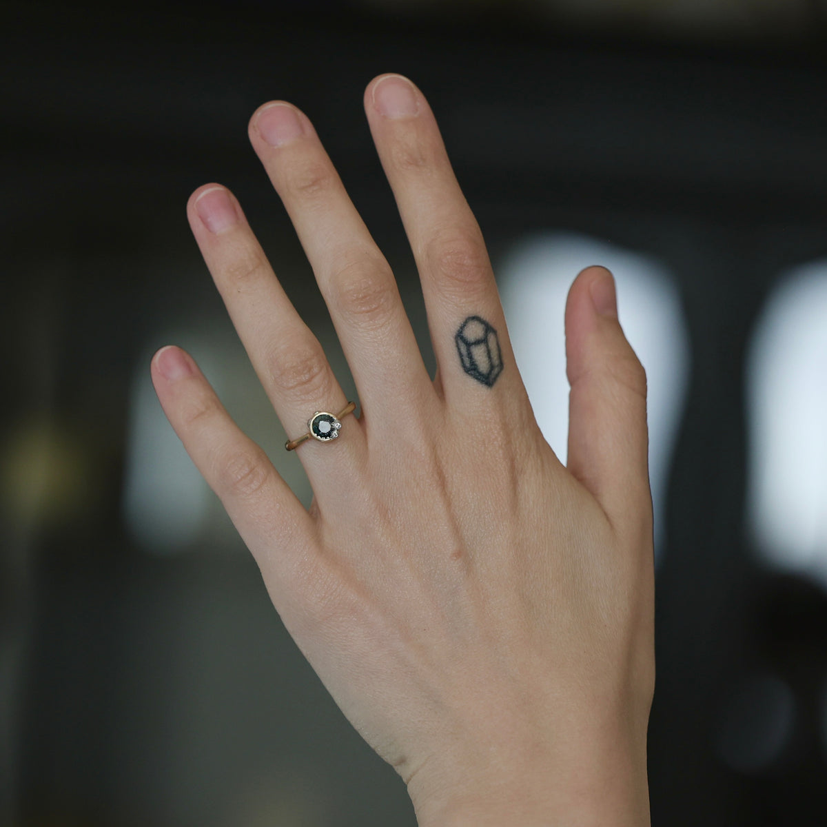 Hand wearing gemstone bezel set ring. 