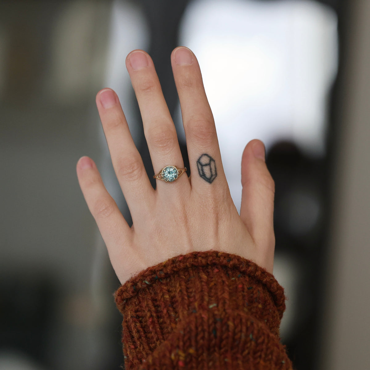 Hand wearing blue gemstone ring. 