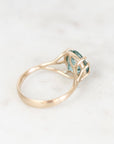 Ring turned away with gold branchy prong setting. Stone is blue background is white. 