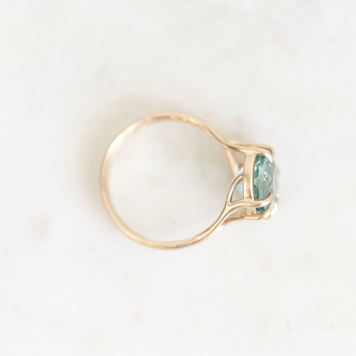 Ring from above. Gold with branchy prongs. Stone is blue background is white. 