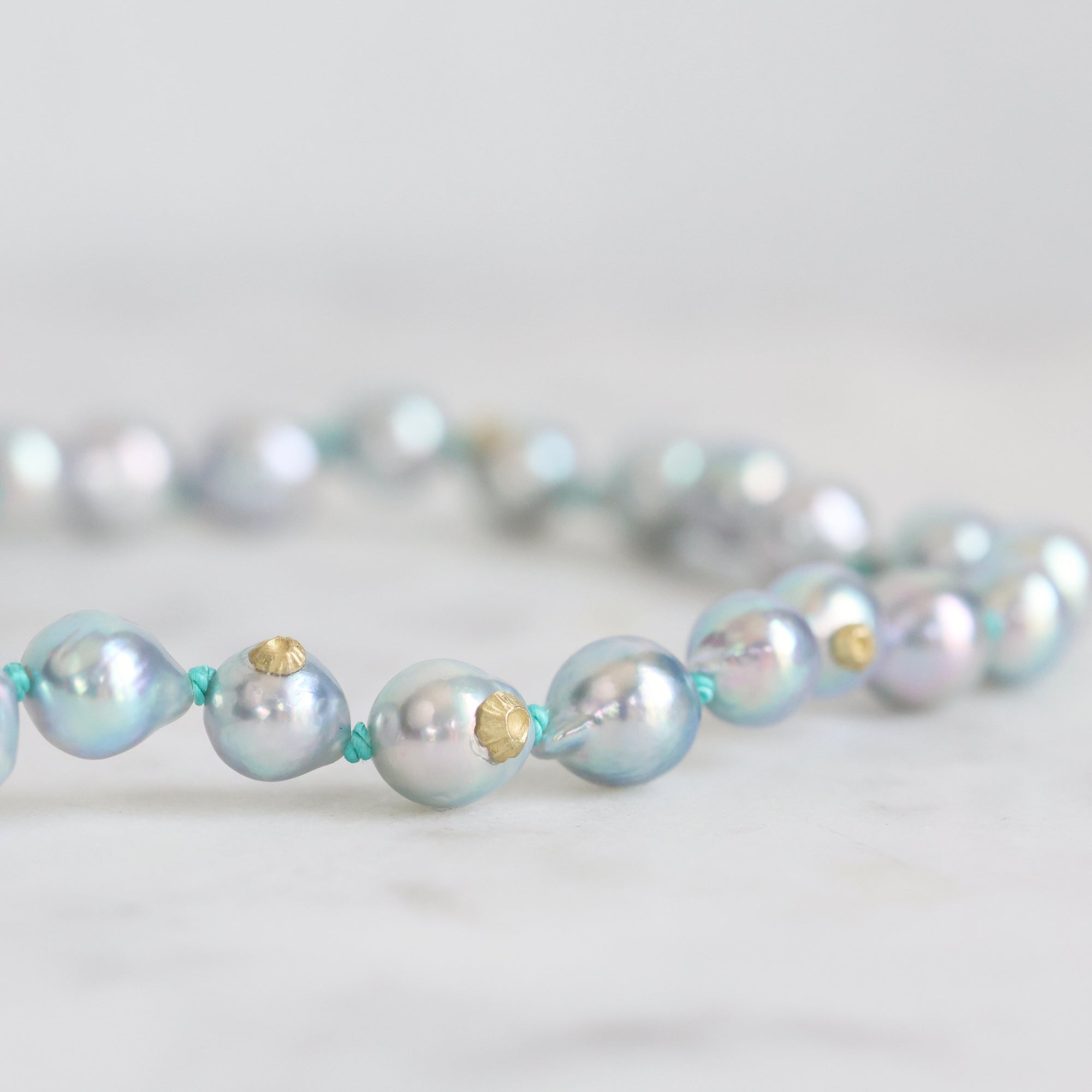Pearl necklace with gold accents on a light gray background