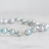 Pearl necklace with gold accents on a light gray background