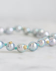 Pearl necklace with gold accents on a light gray background