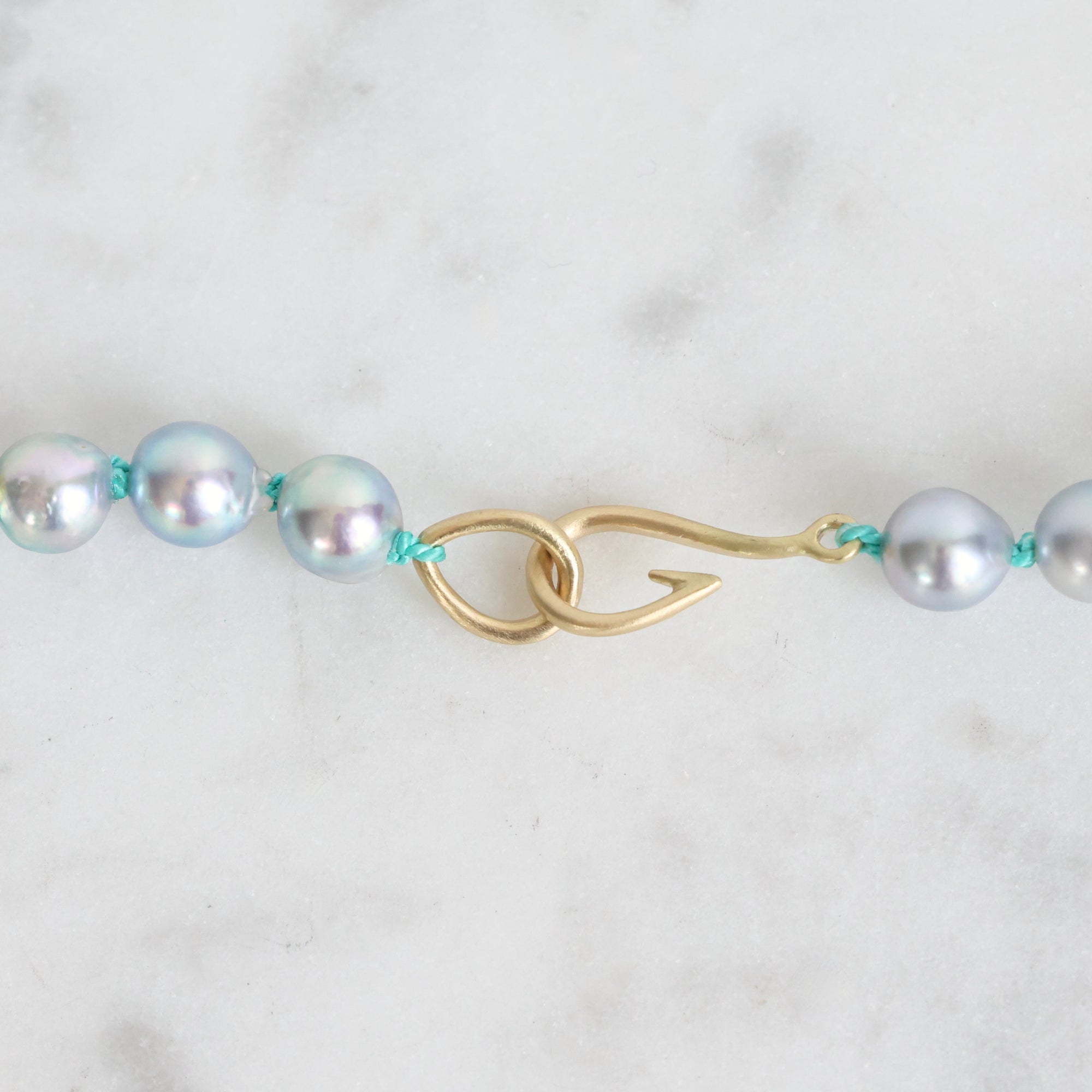 Pearl necklace with a gold clasp on a light gray background