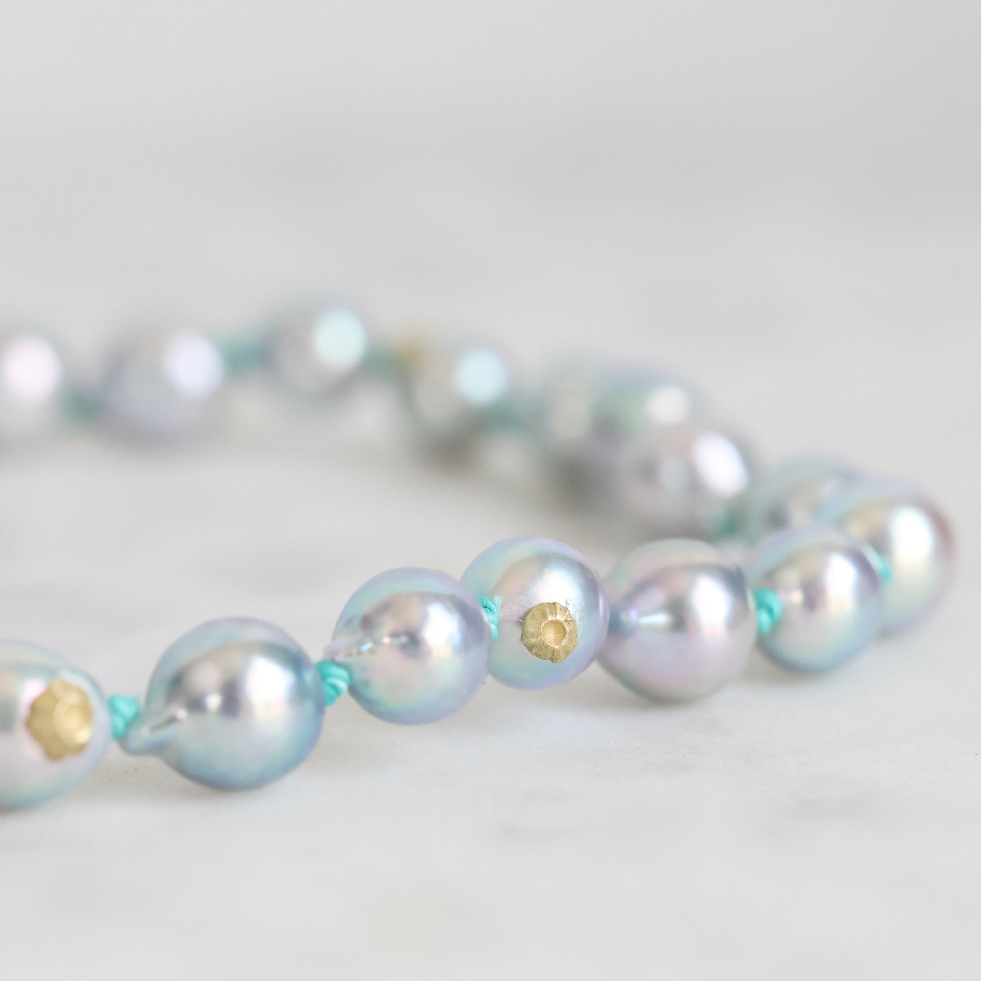 Pearl necklace with gold accents on a light gray background