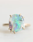 Opal ring set in gold prongs. The opal is colorful with flashes of green, blue, yellow, and pink. 