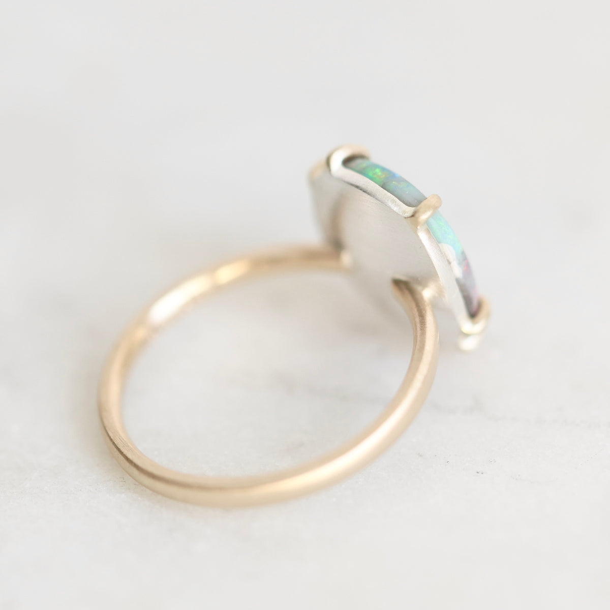 Back of ring with gold prongs and gold band. Backplate is silver. Against a white background. 