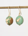 Pair of earrings with green and gold beads on a white background