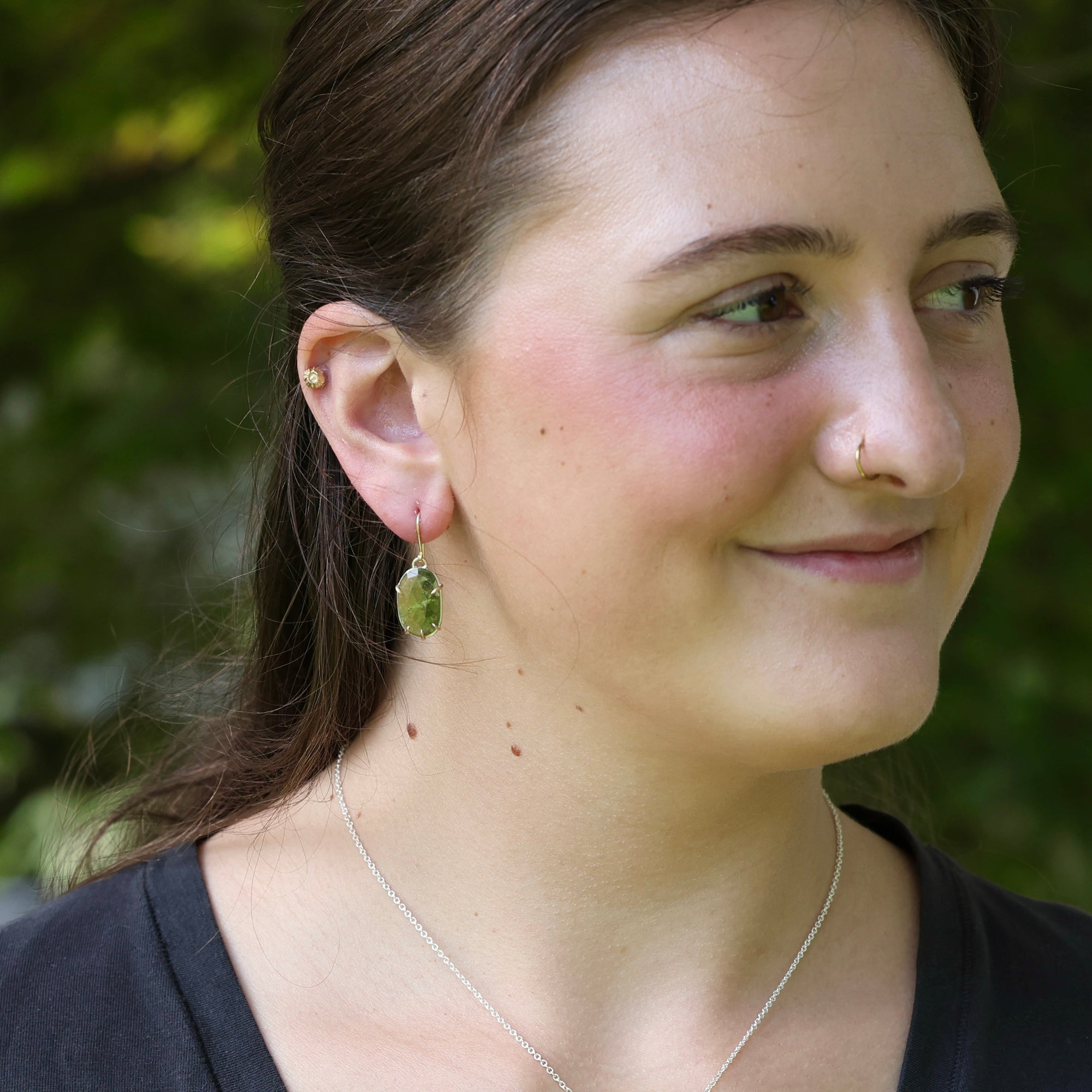 Bright green drop earrings on person