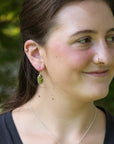 Bright green drop earrings on person