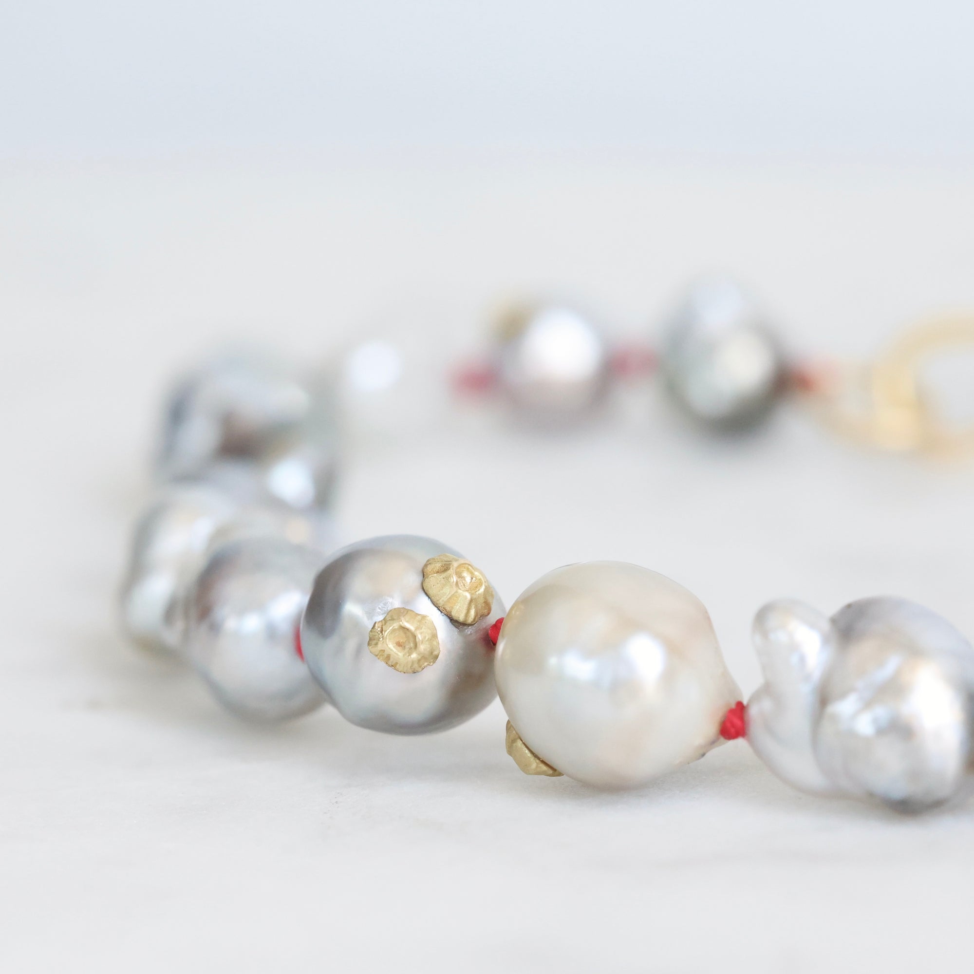 Close-up of a pearl bracelet with gold accents on a light background