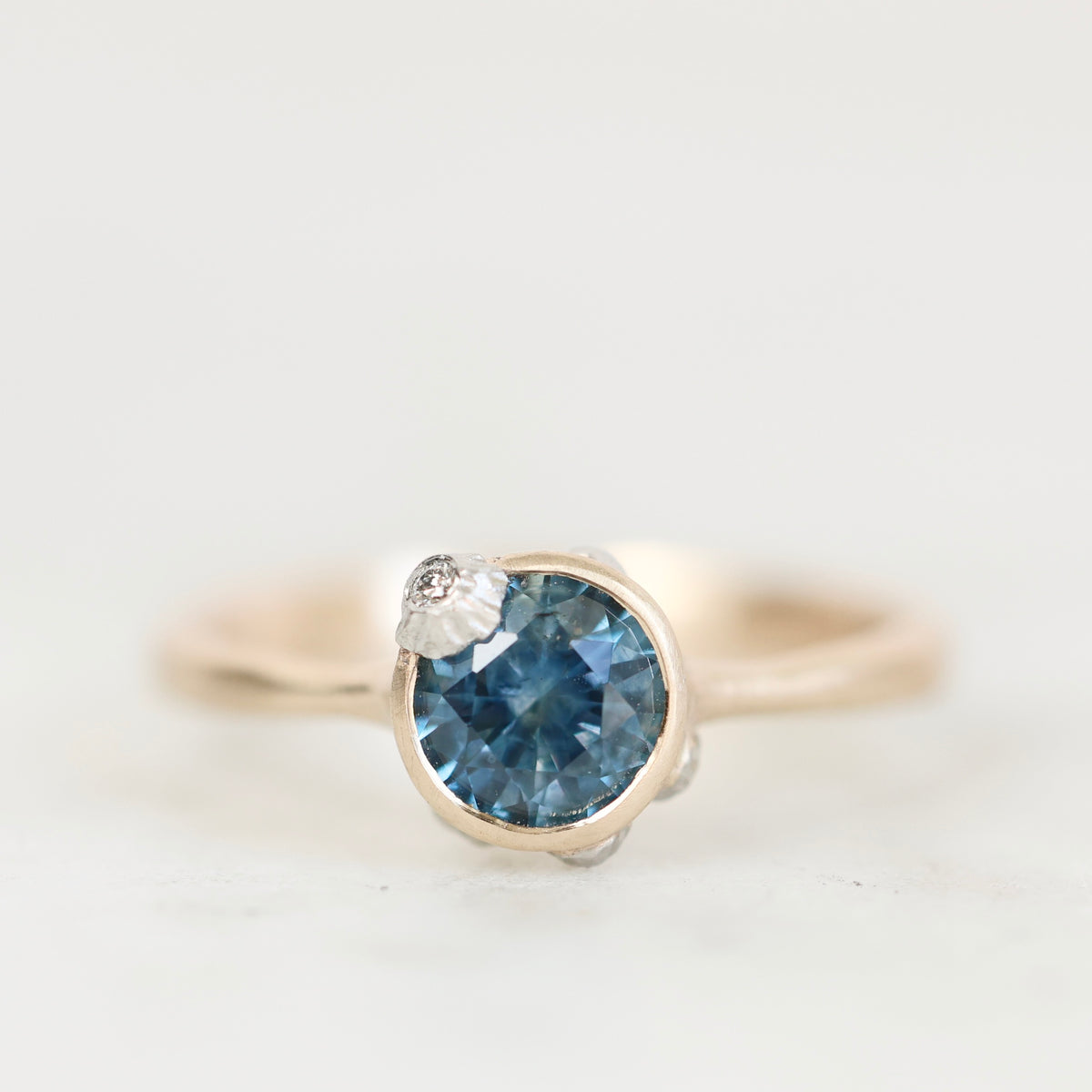 Deep blue gemstone ring with barnacle details against a plain background. 