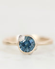 Deep blue gemstone ring with barnacle details against a plain background. 