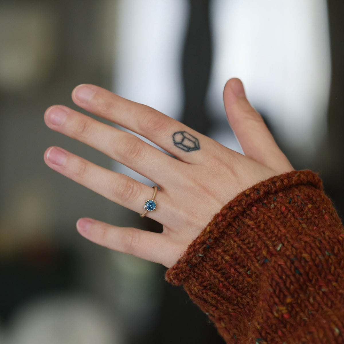Hand wearing blue gemstone ring. 