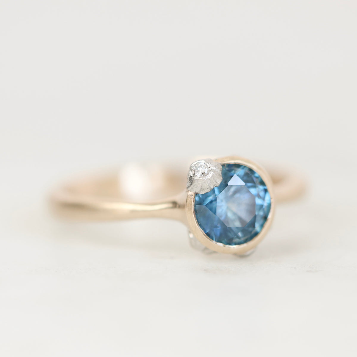 Blue gemstone ring with gold setting and barnacle details. 