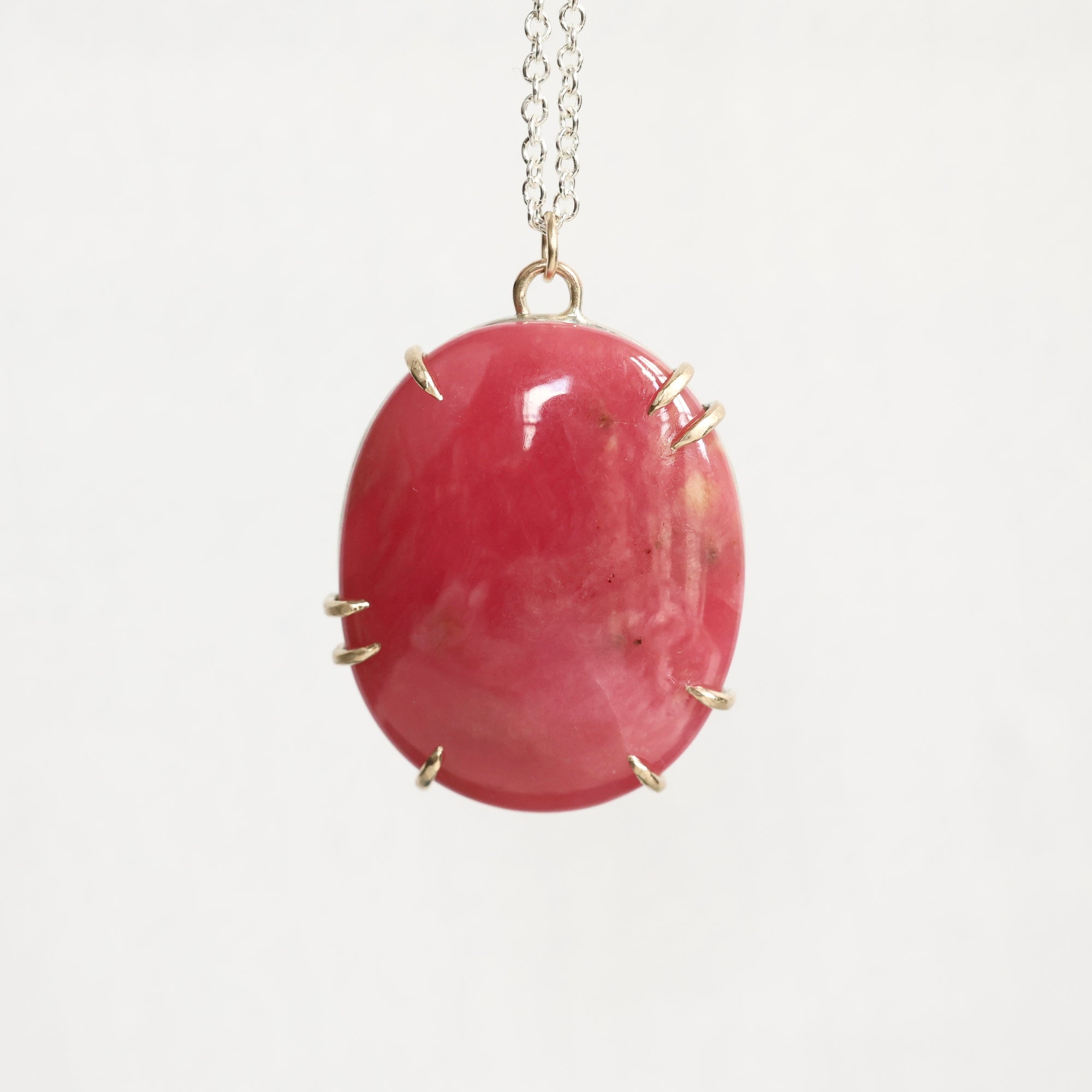 Pink oval stone pendant on a chain against a white background