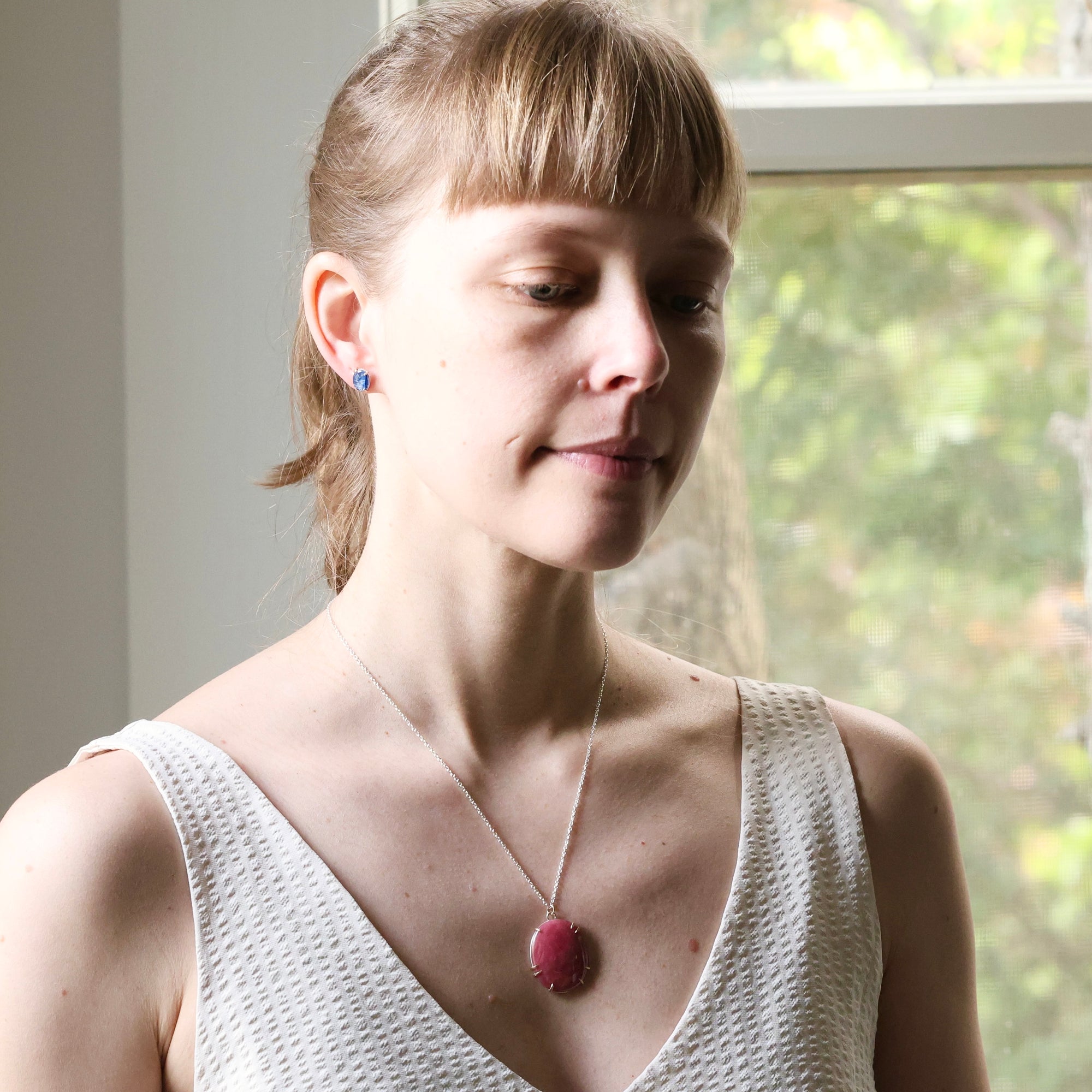 Woman wearing a necklace with a pink pendant indoors