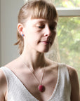 Woman wearing a necklace with a pink pendant indoors