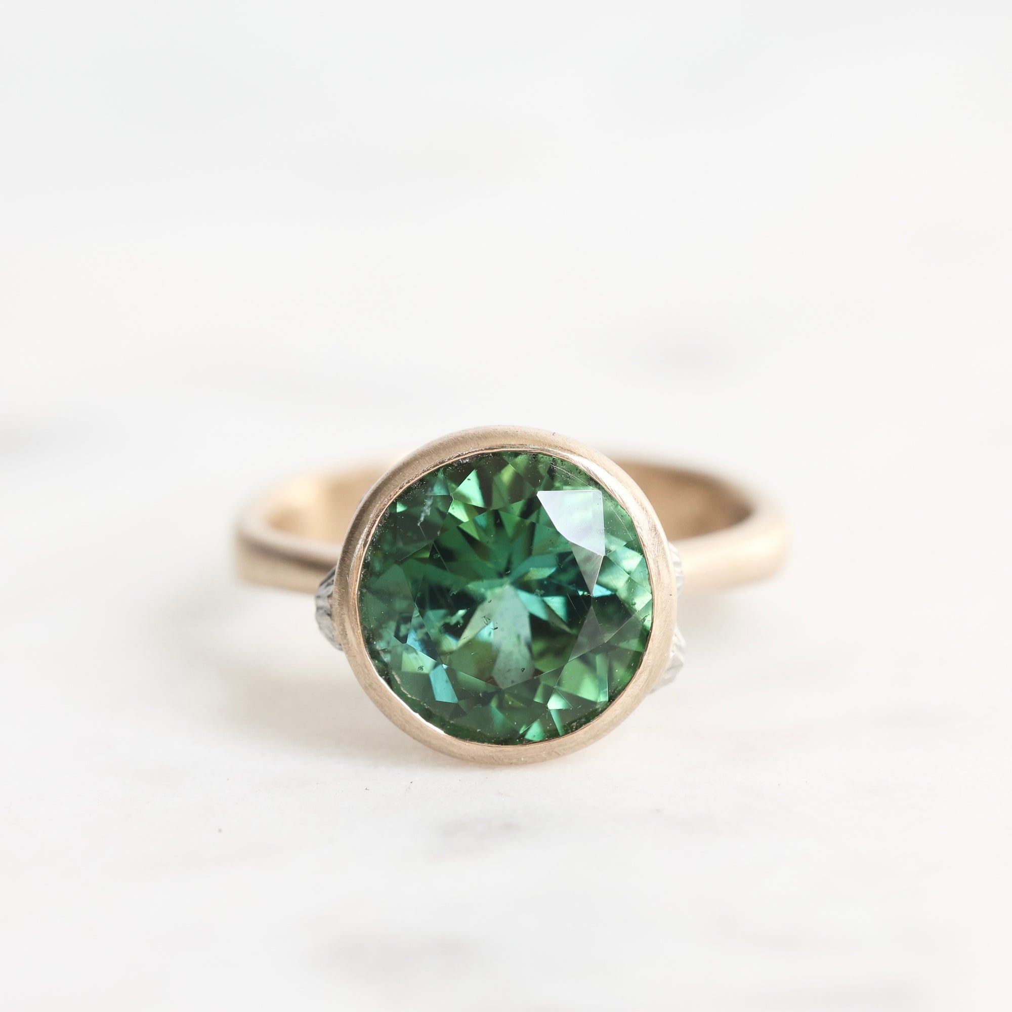 Gold ring with a green gemstone on a white background
