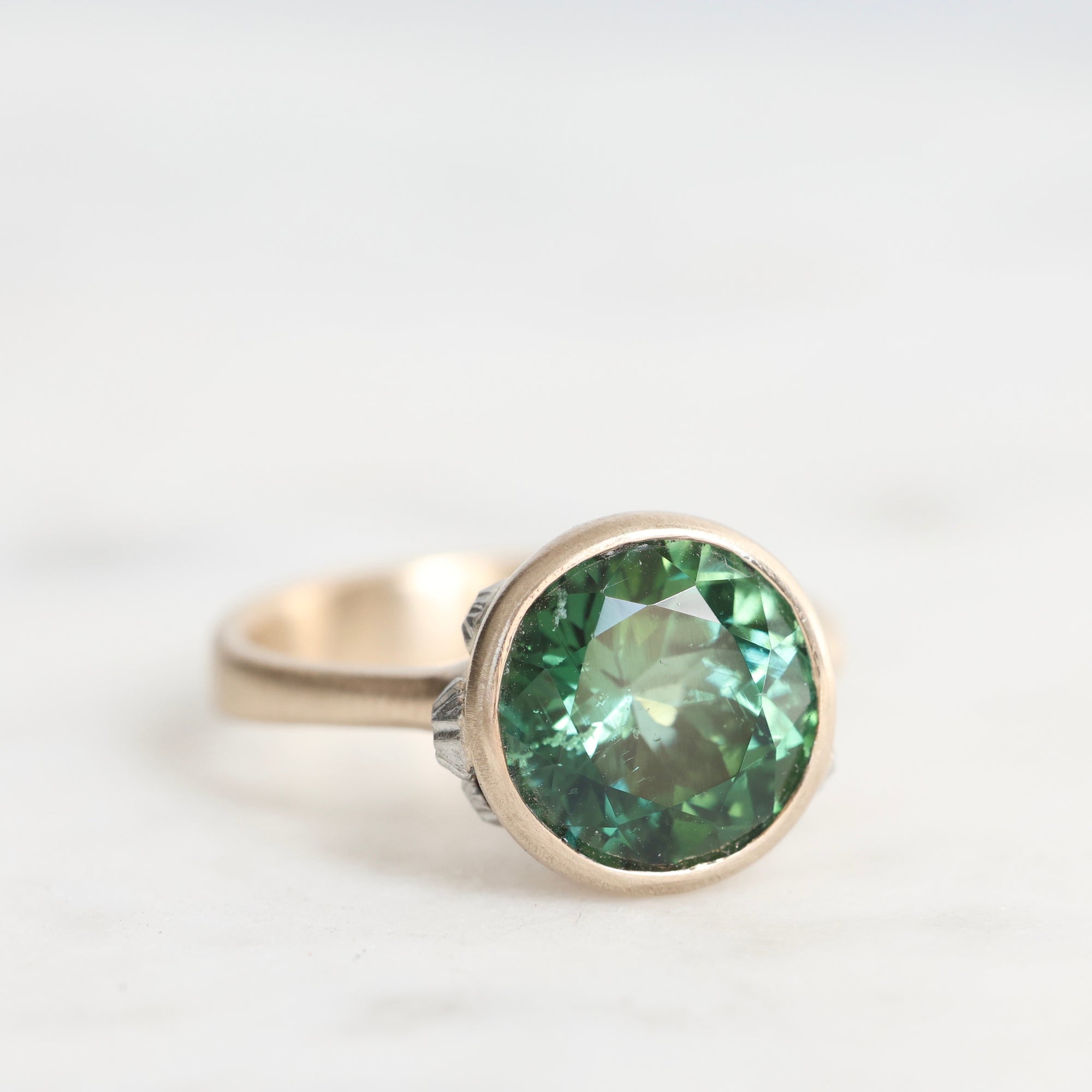 Gold ring with a green gemstone on a white background