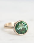 Gold ring with a green gemstone on a white background