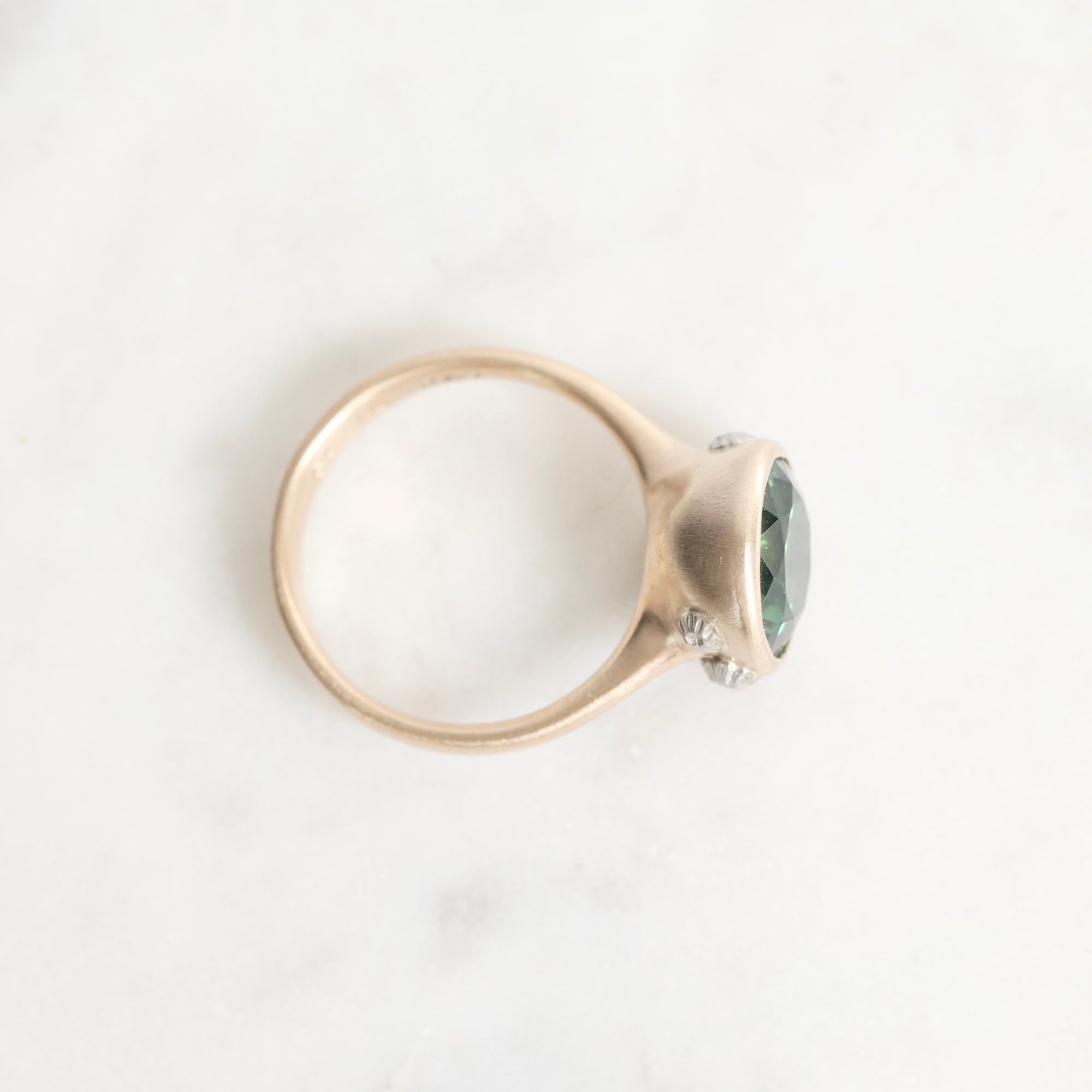 Gold ring with a green gemstone on a white background