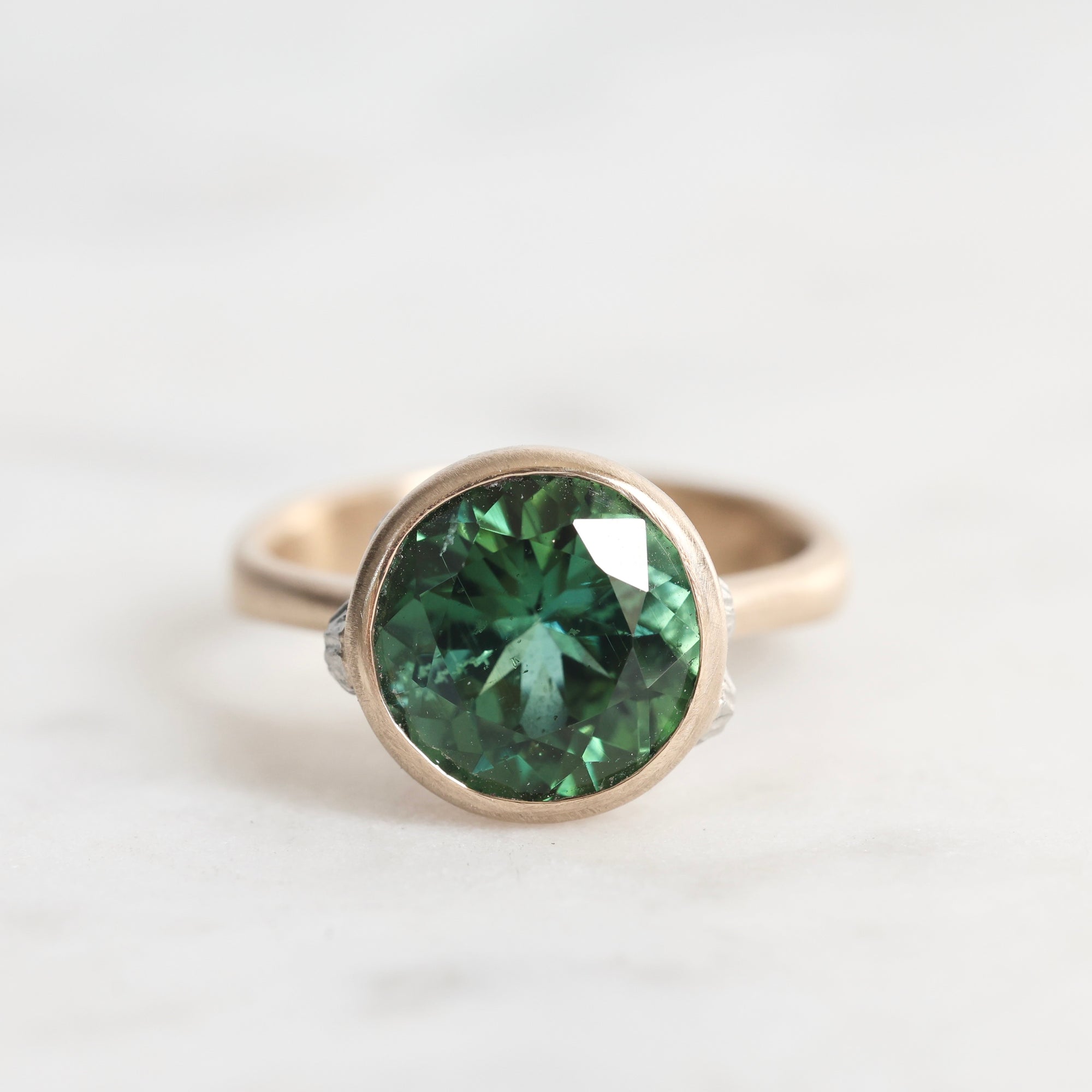 Gold ring with a green gemstone on a white background