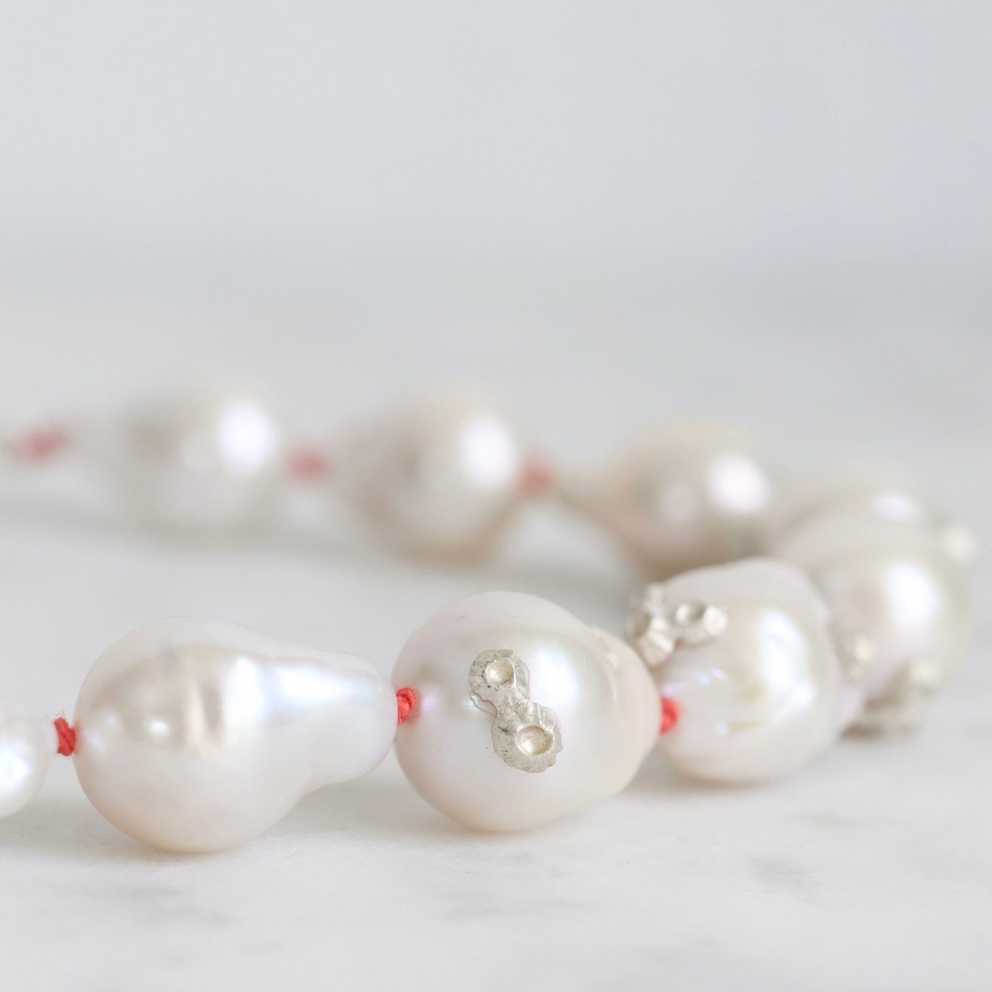 Pearl necklace with silver clasp on a light gray background