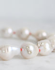 Pearl necklace with silver clasp on a light gray background