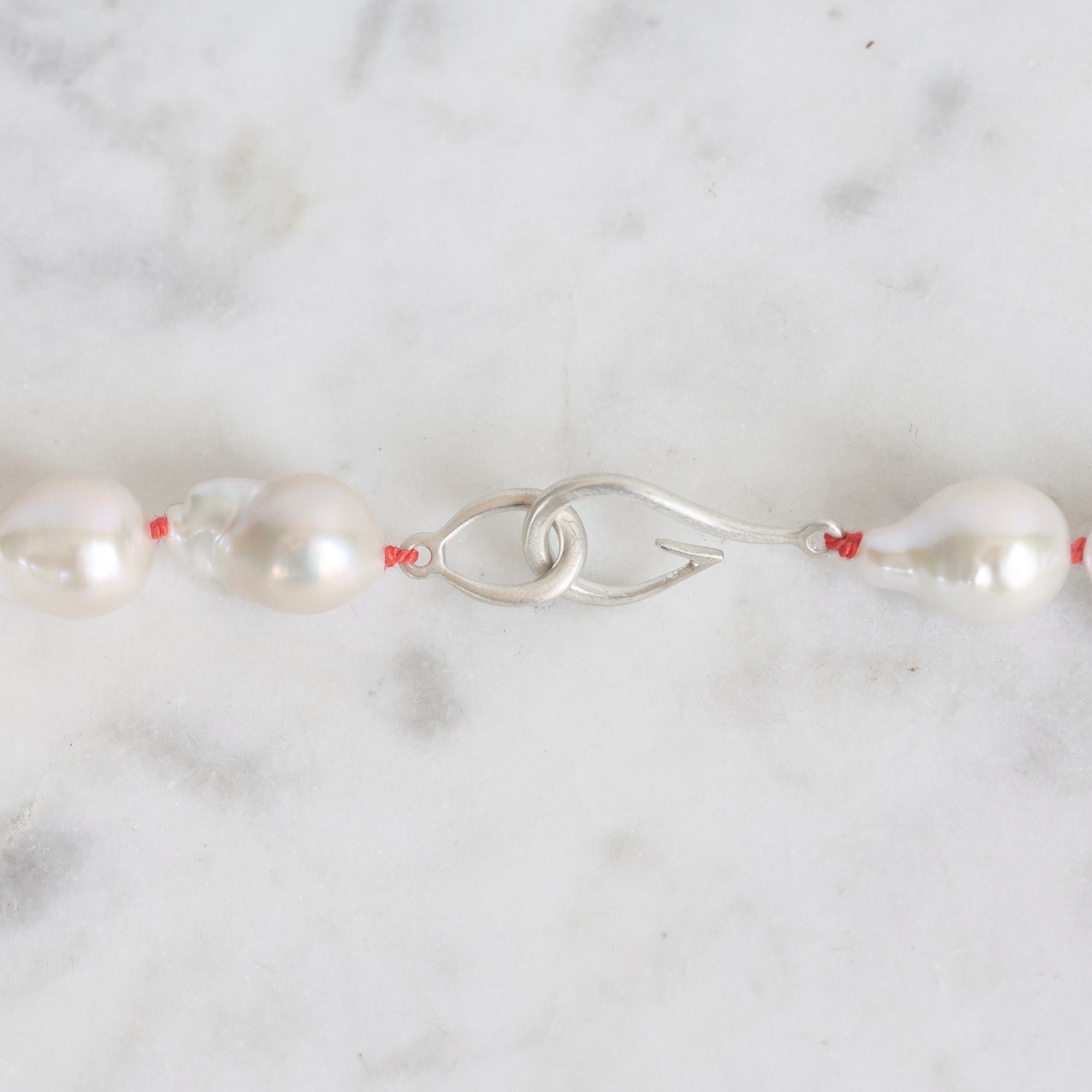 Pearl necklace with a silver clasp on a marble surface