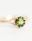 A silver ring with a round-cut green gemstone in a prong setting, photographed on a clean white background.
