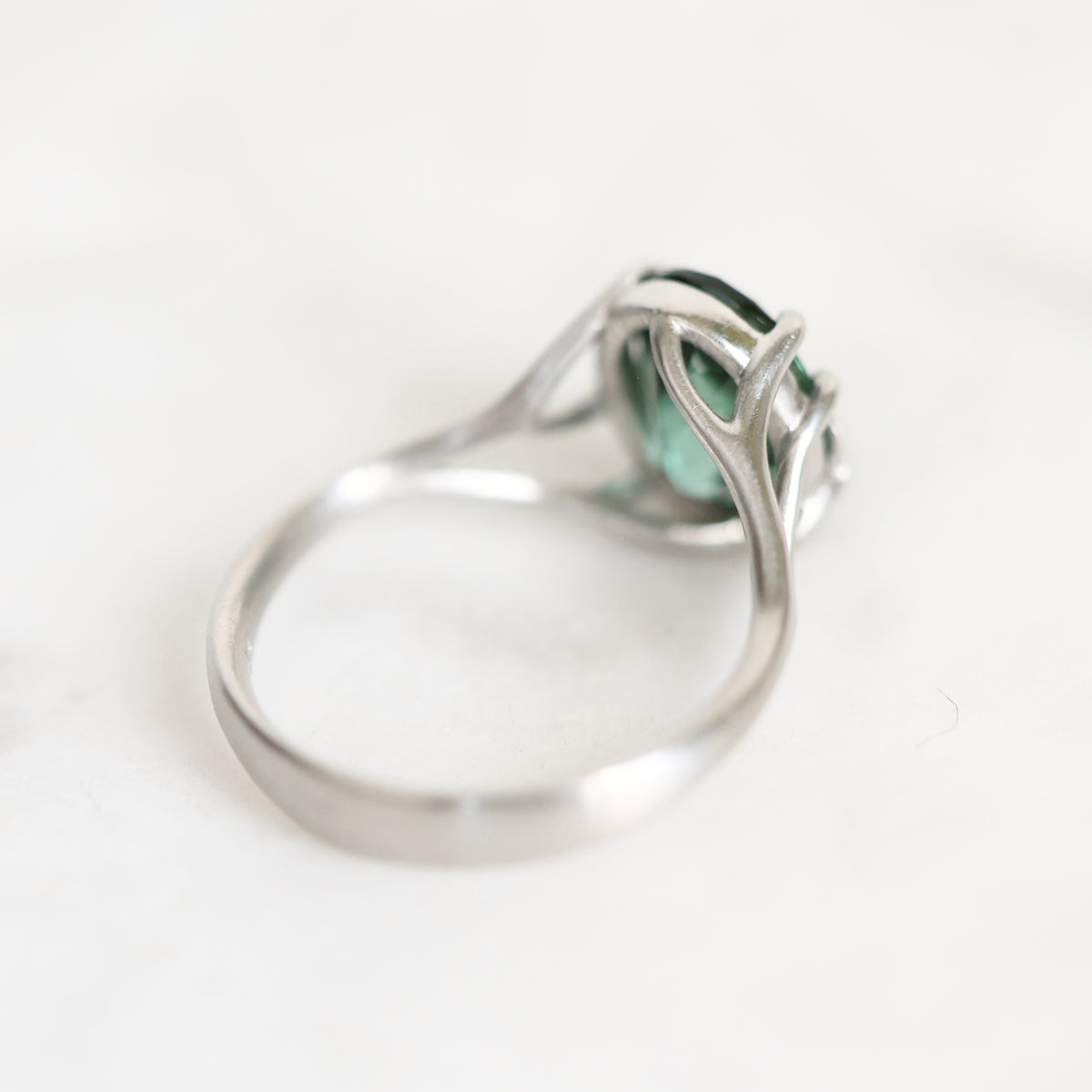 A silver ring with a green marquise-cut gemstone, photographed on a clean white background.