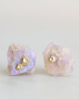 Raw opal studs with gold barnacle details against a white background. 